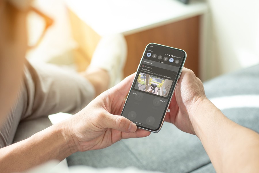 Person holding smartphone with video surveillance footage on display. 