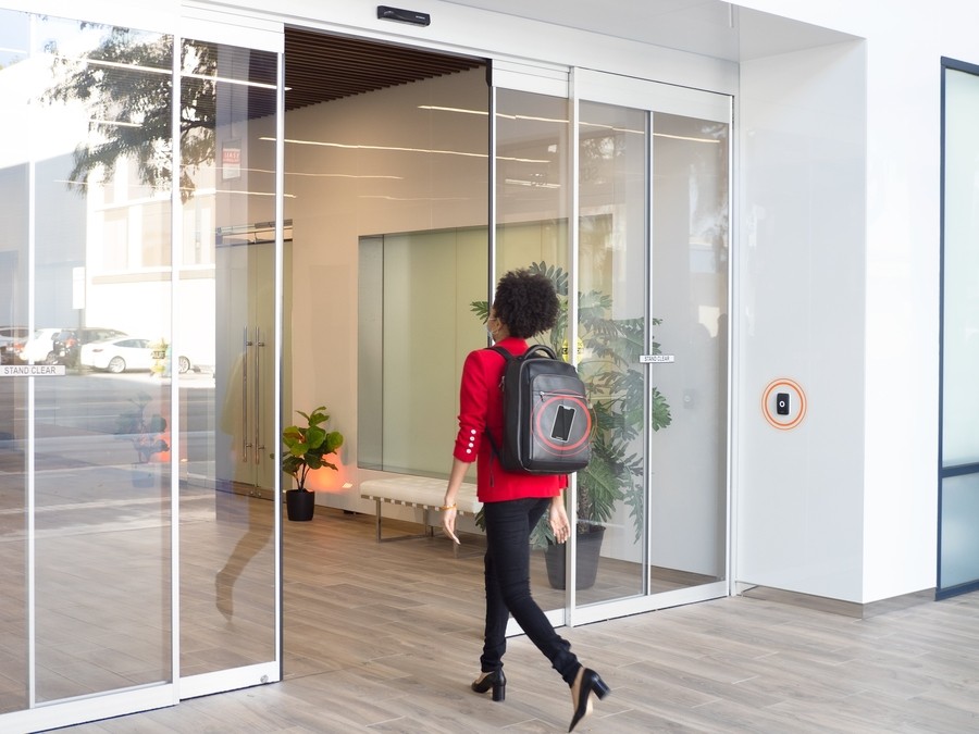 A person walks through automatic entrance doors in a modern building.