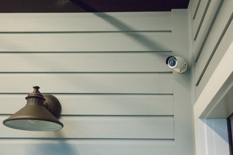 A security camera is mounted over an entryway to a home. 